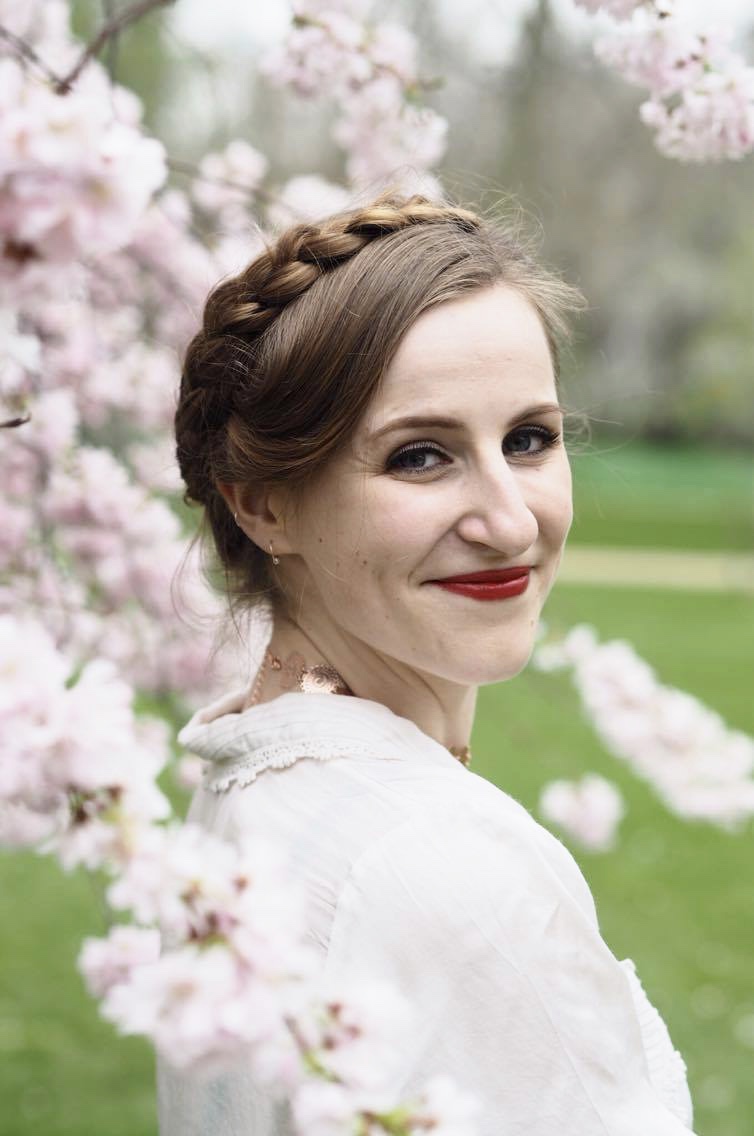 woman with milkmaid braids surrounded by blossom trees