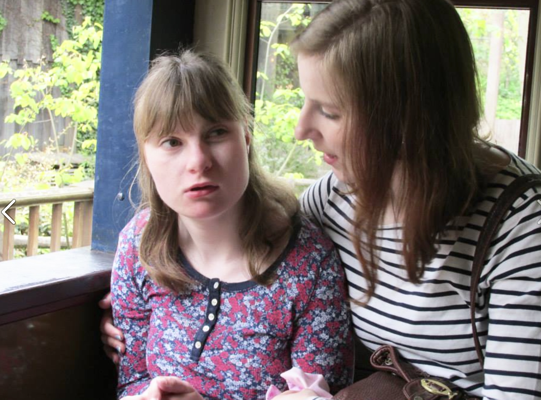 two women with arms round each other, one in a wheelchair