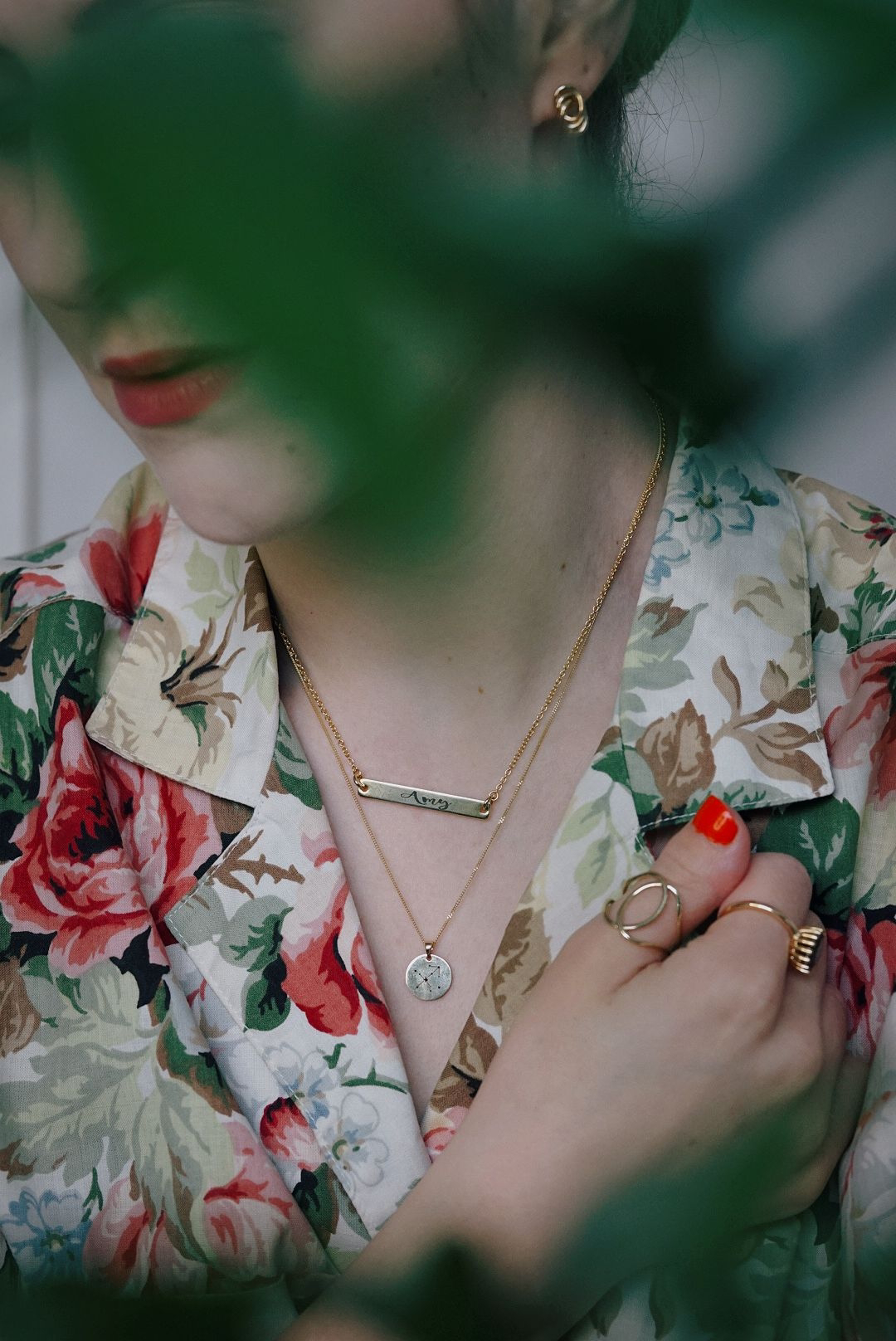 close up of girl in floral blouse wearing two gold necklaces