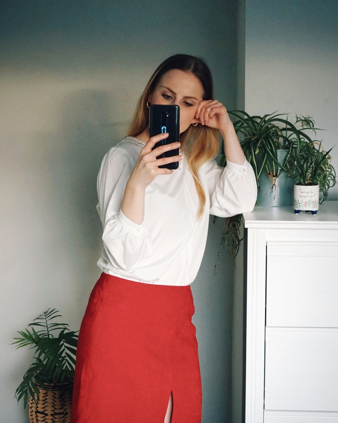 Amy is wearing a white blouse tucked into a red suede skirt