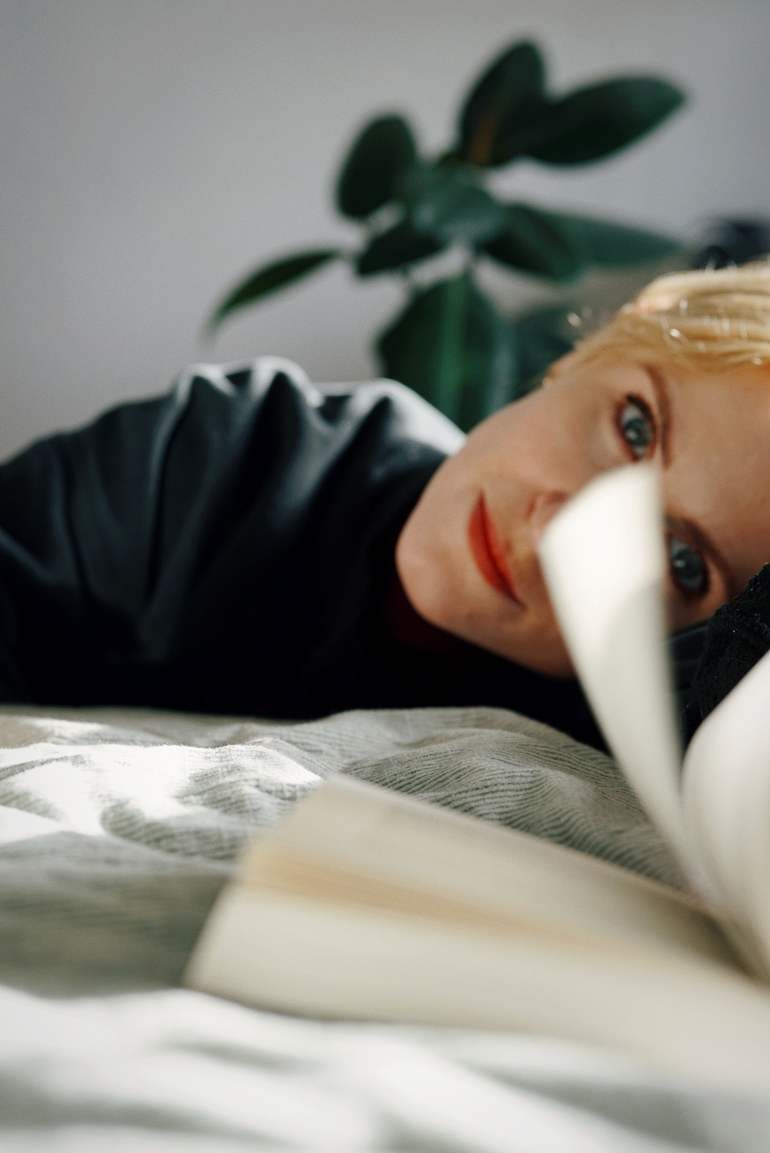 a girl's face partially obscured from view by a book and the pages turning