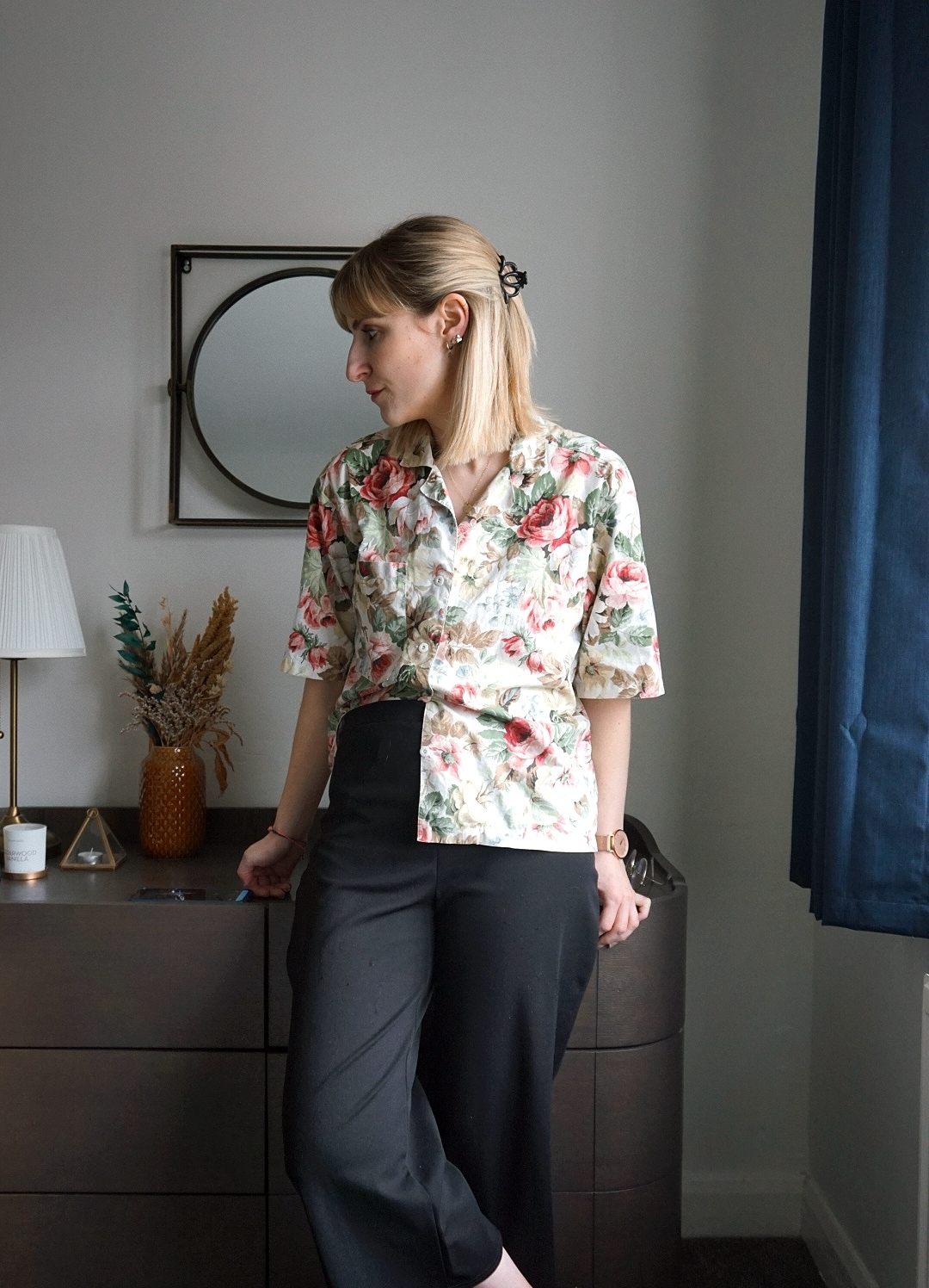 Outfit photo (indoor in front of a dark chest of drawers), wearing a floral blouse and black cropped culottes