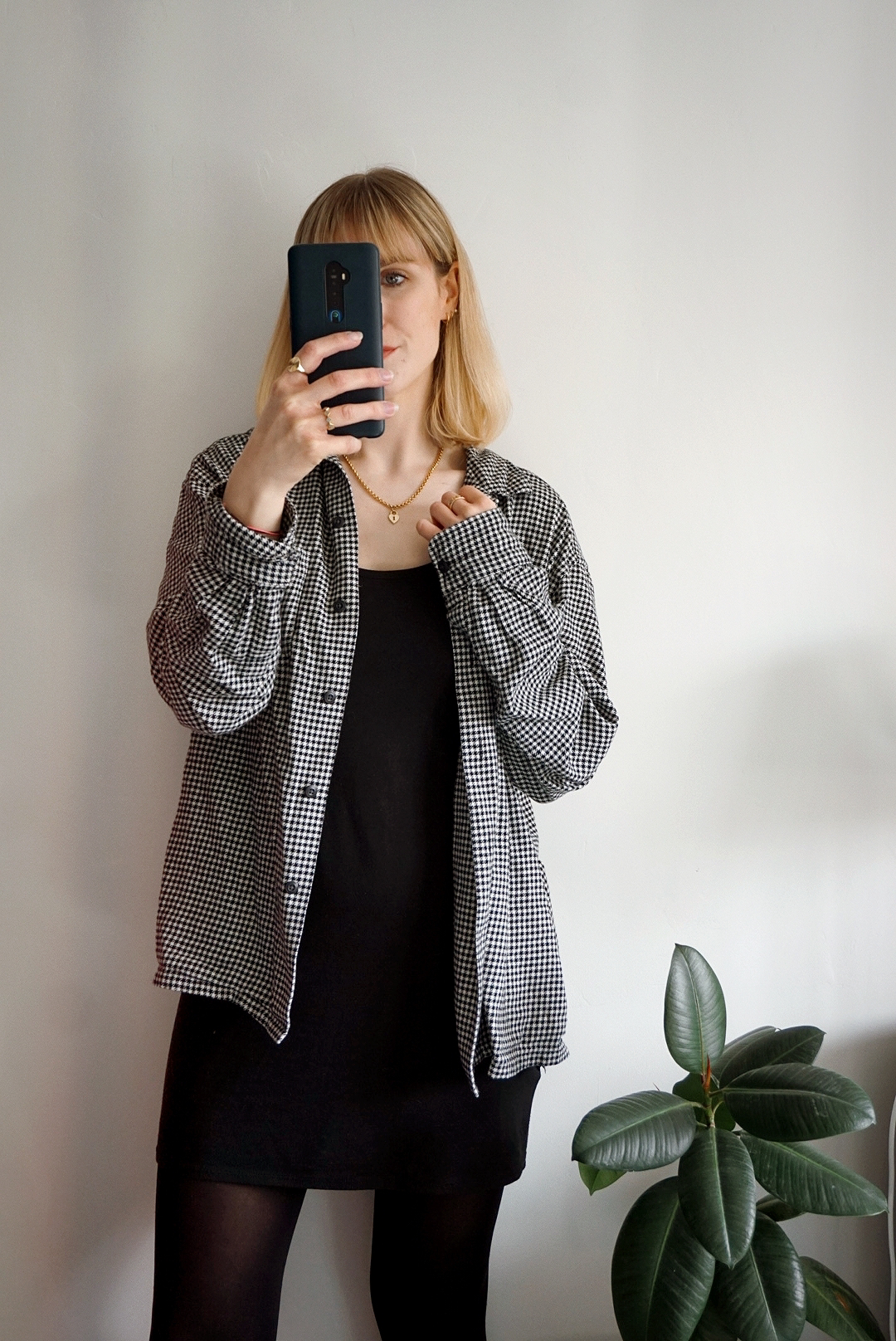 Outfit photo (indoor against cream wall), wearing a plain black cotton dress, black tights and an open black and white check shirt, rolled up at the sleeves a little