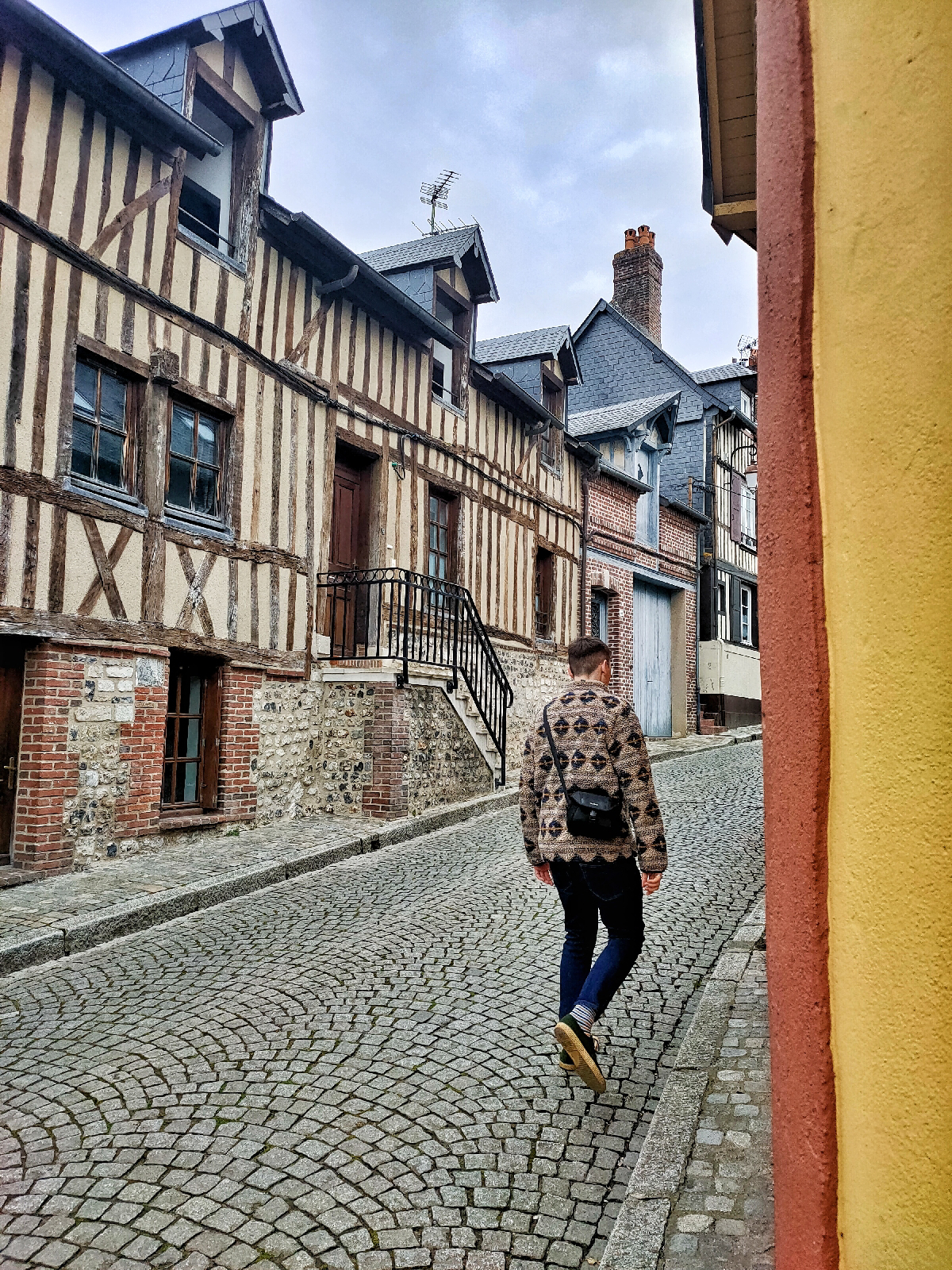 a man is walking up a cobbled hill on an old French street