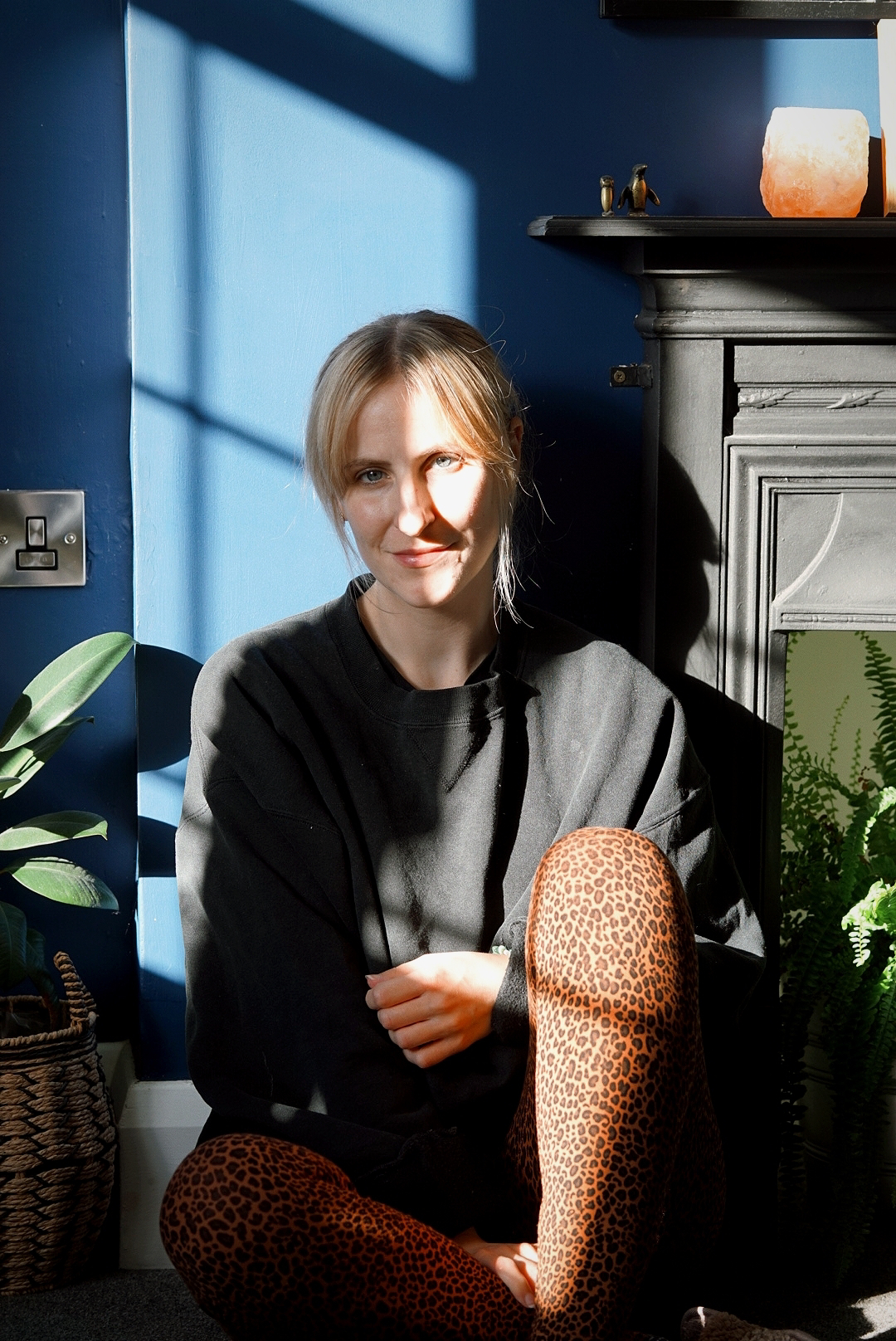 Amy is sitting, wearing a black oversized sweatshirt and leopard print leggings