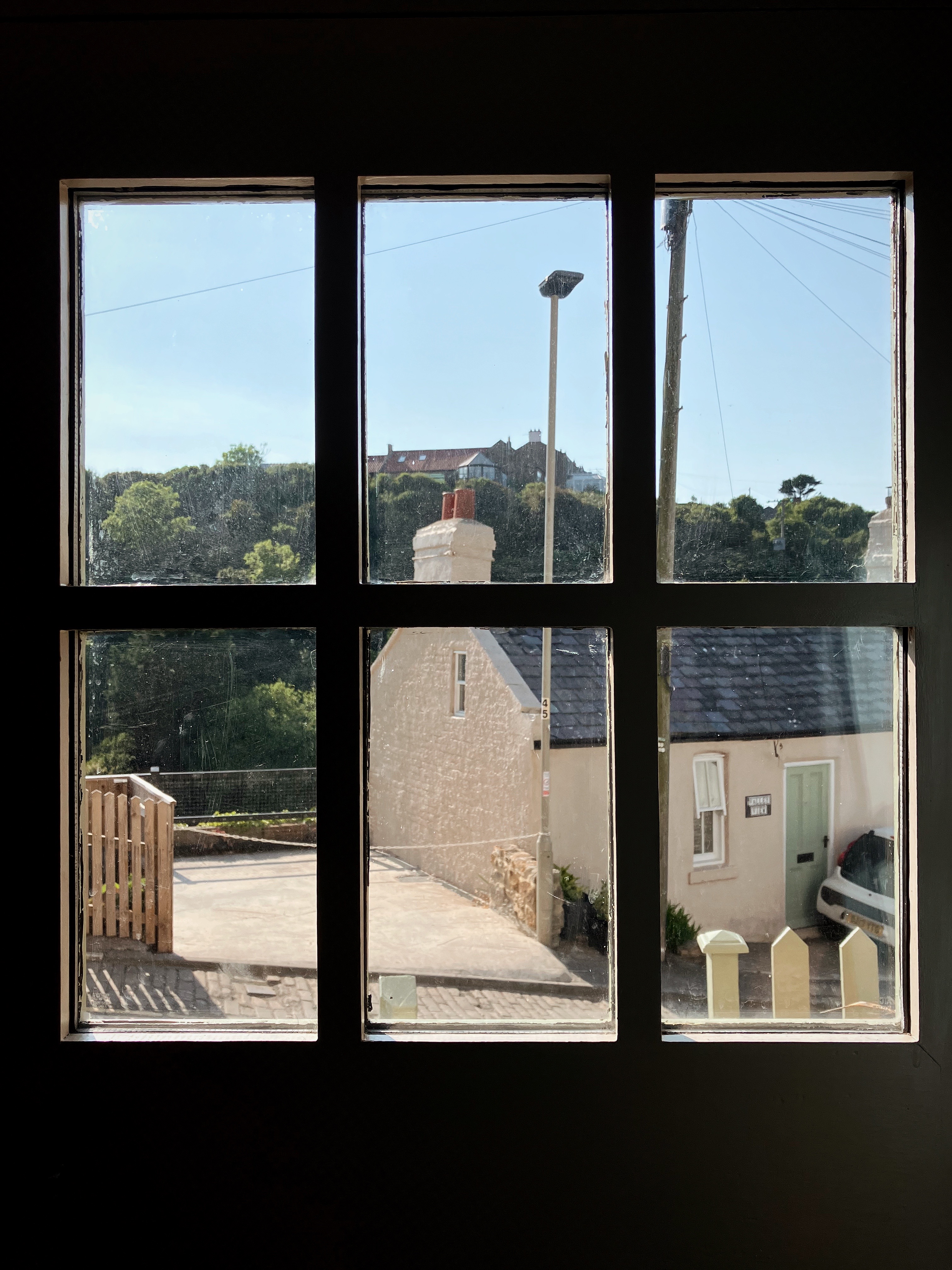 the view out of a window across a valley, there is a cottage in the foreground