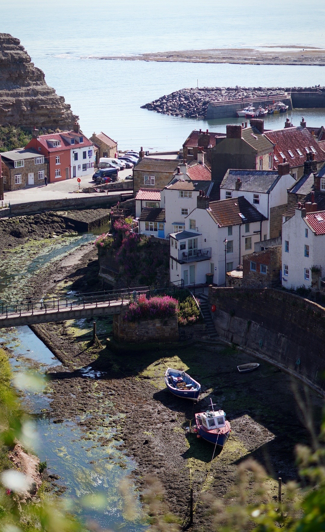 a view down a valley with cottages on either side looking out to sea on a sunny day