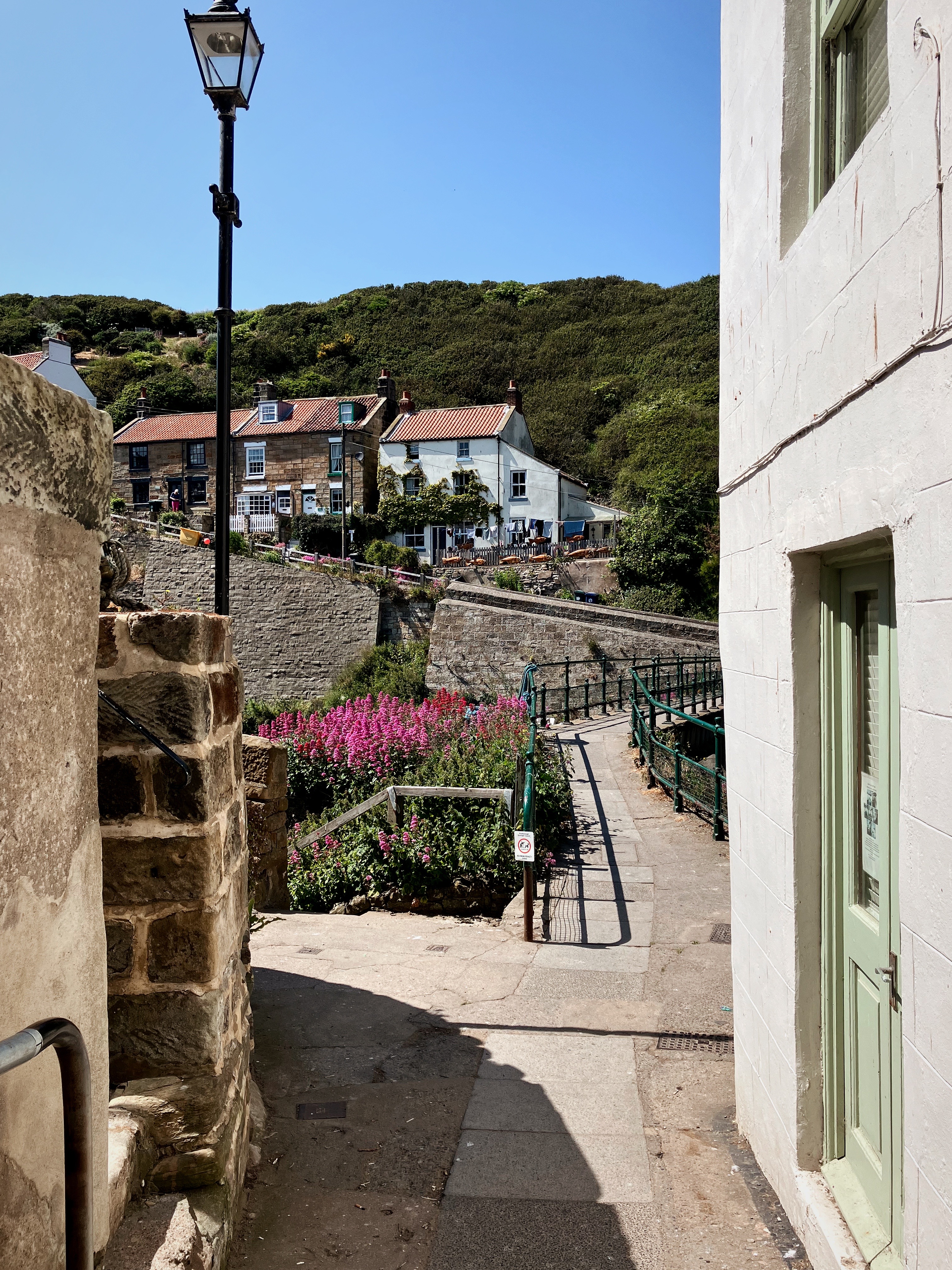 view between some houses towards a bridge, across which is a row of cottages
