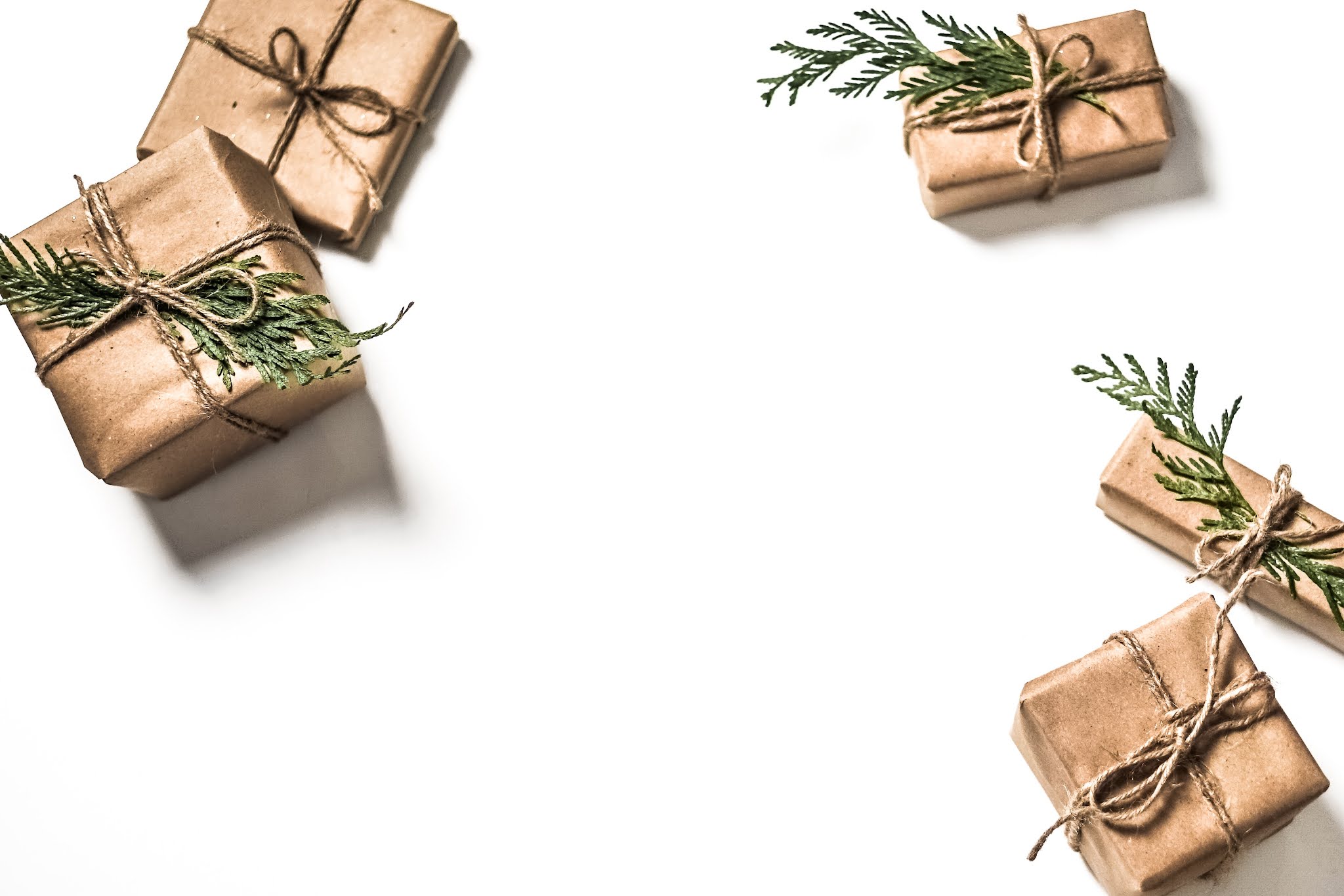 neatly wrapped Christmas presents in brown paper and string on a white background