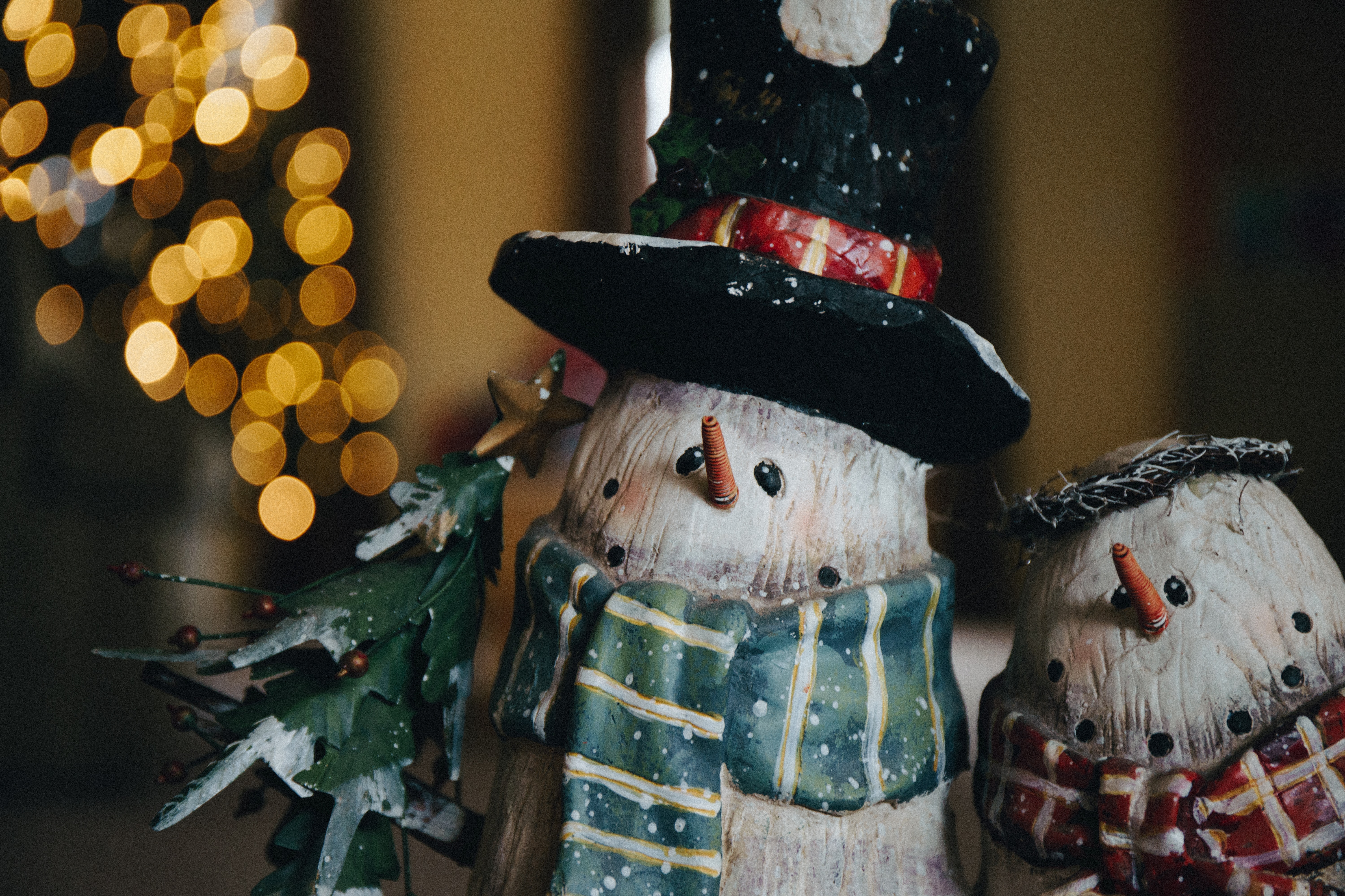 two snowman ornaments in front of some christmas lights