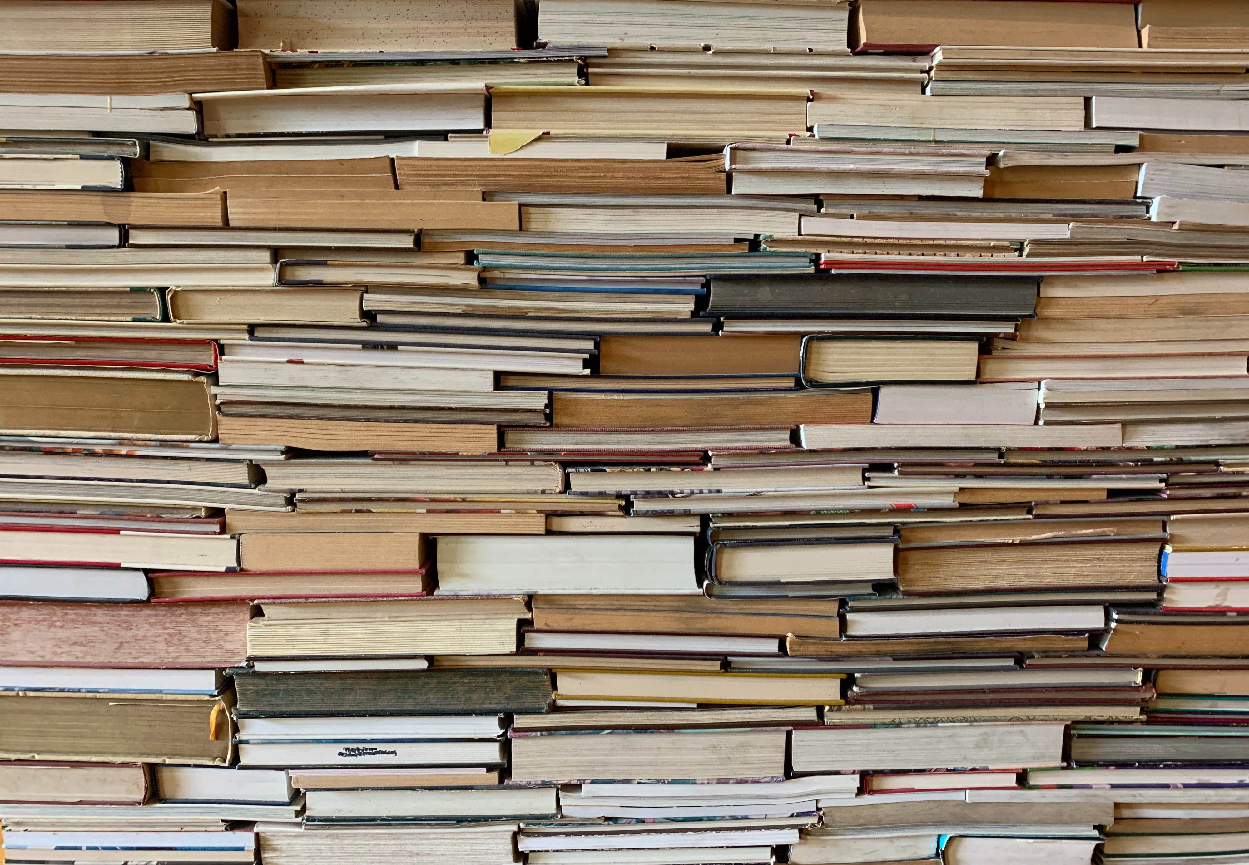 books upon books stacked on a bookshelf, pages facing outwards