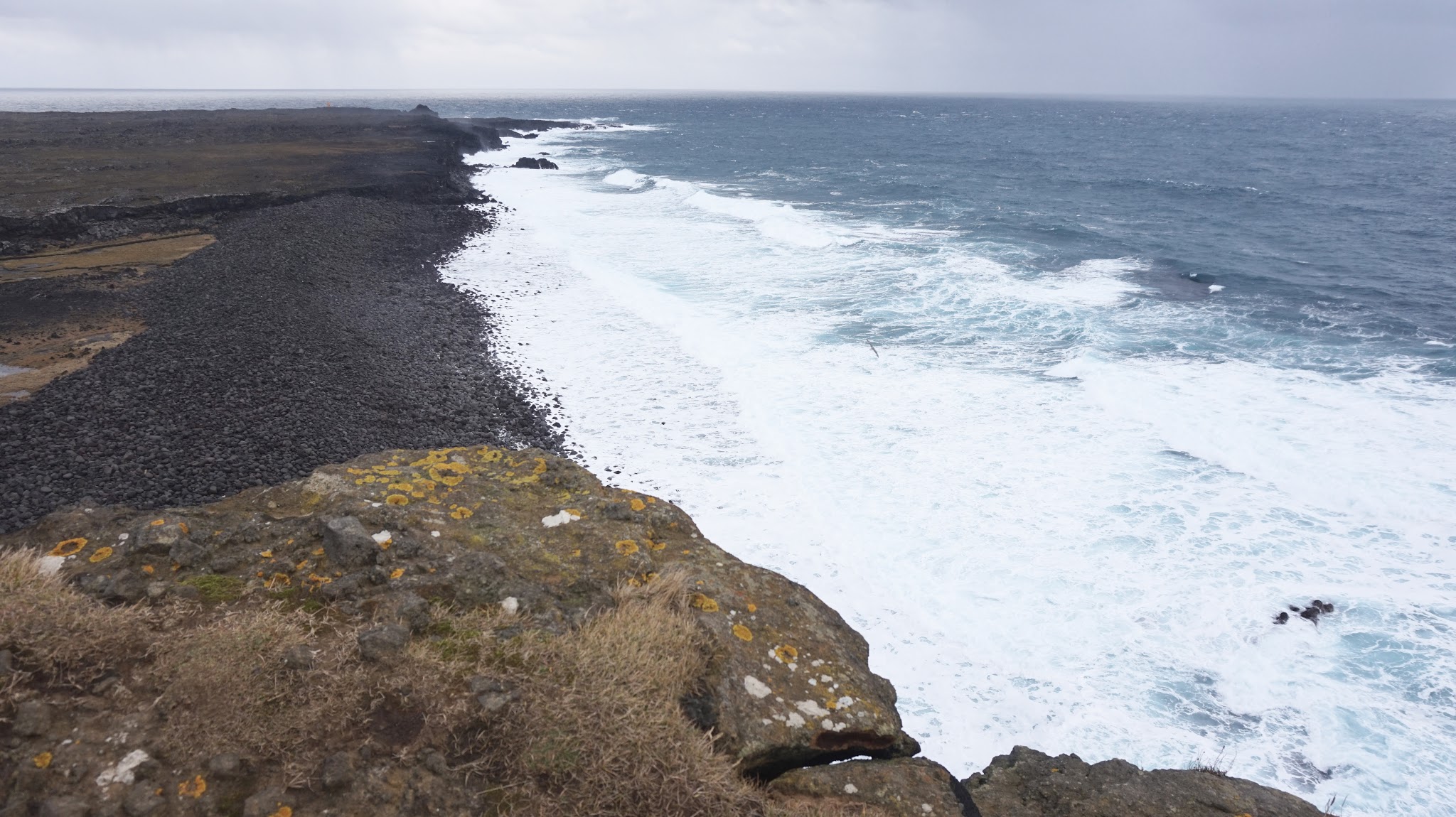 blue icy choppy waves against black rocks