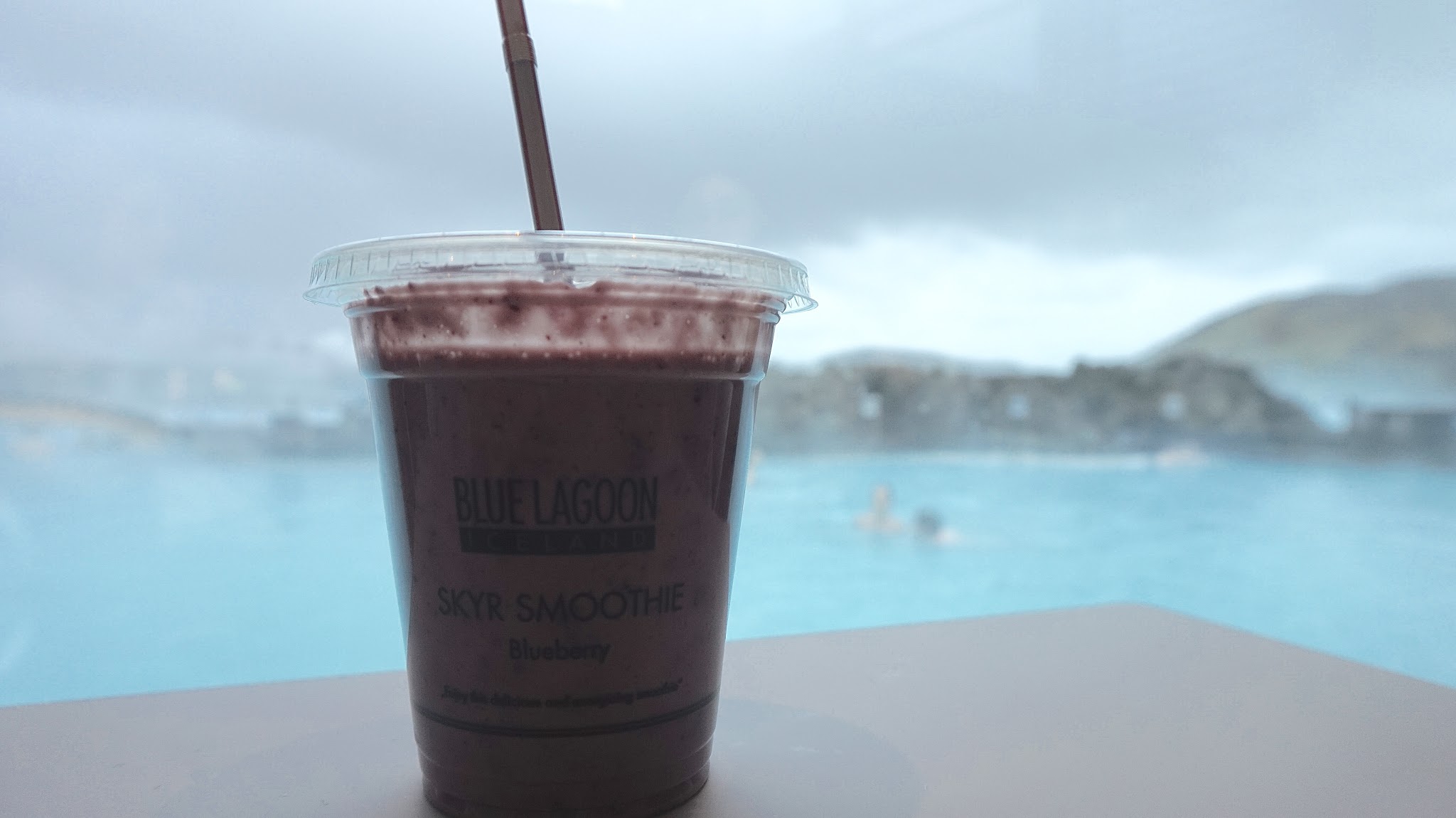 red smoothie against backdrop of blue water