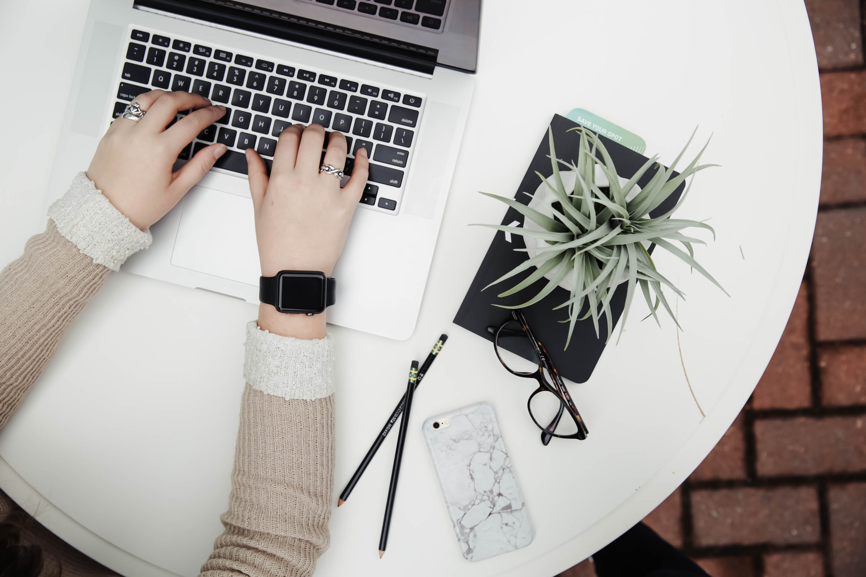 view from above of girl at laptop with phone and plants