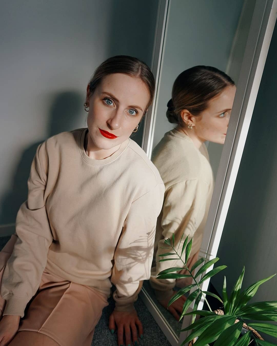 woman wearing red lipstick sat on the floor next to a mirror
