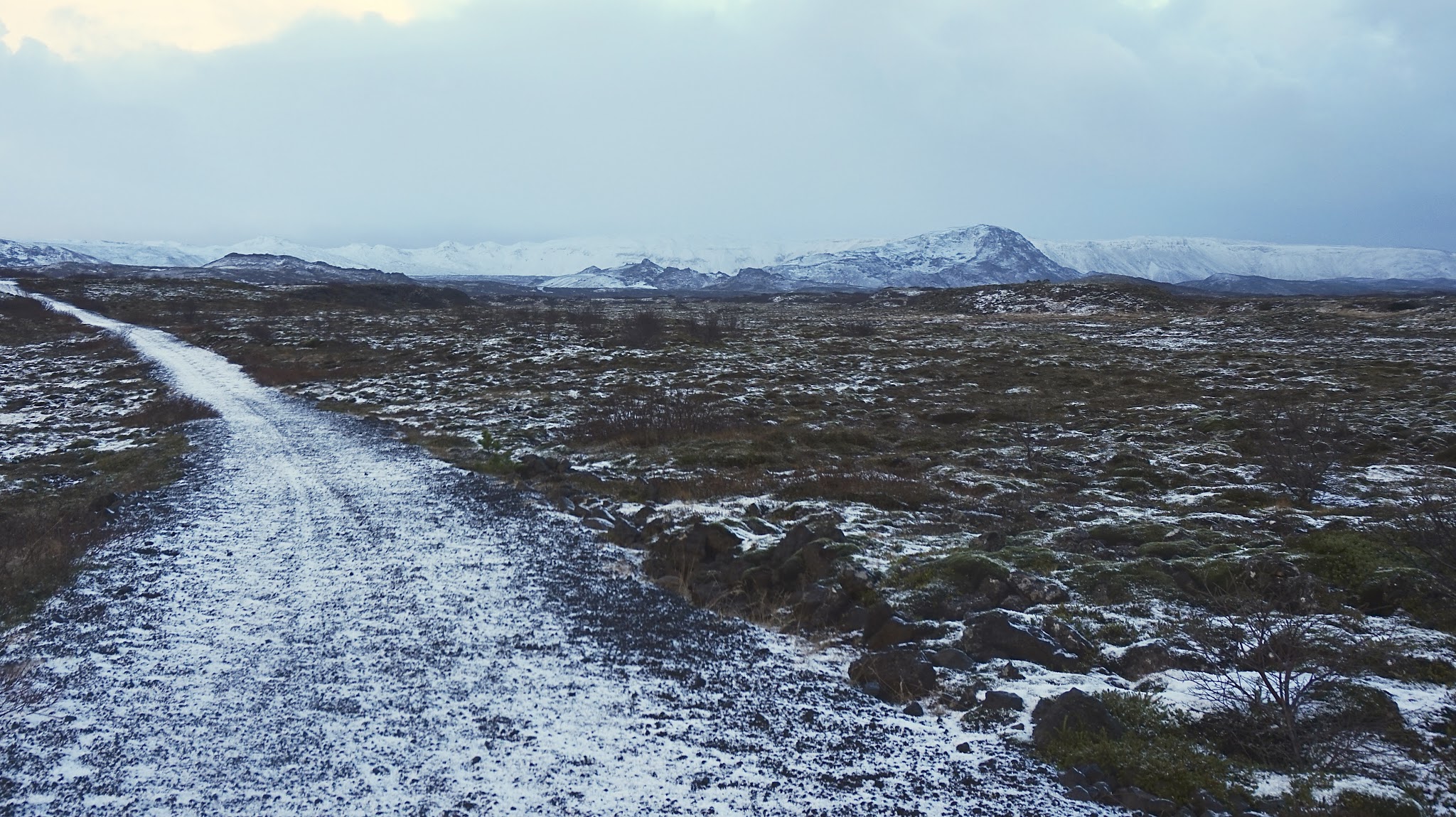 snowy path leading up to snowy mountains, moody sky