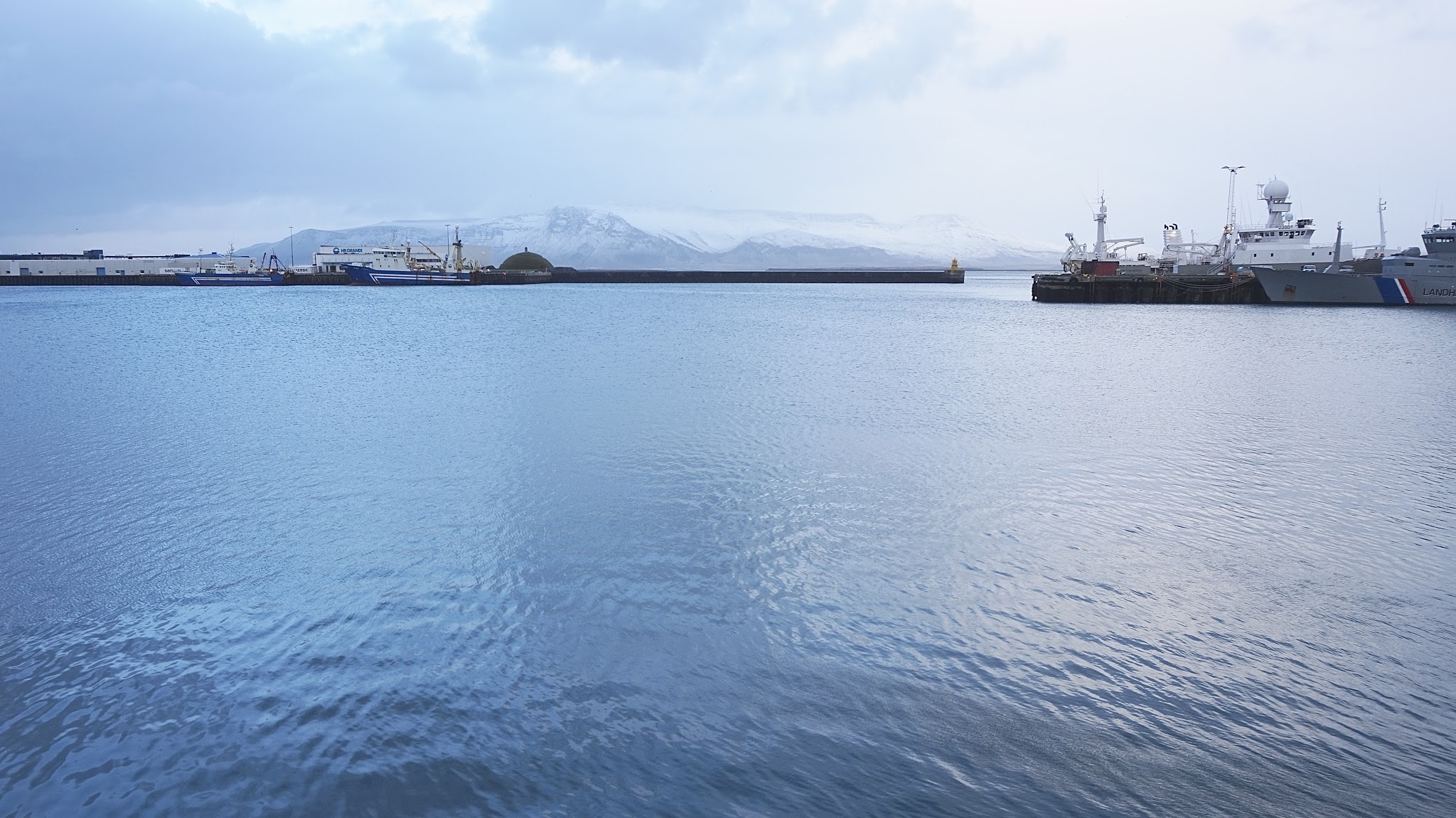 blue water, snowy mountains in the distance, boats out at sea