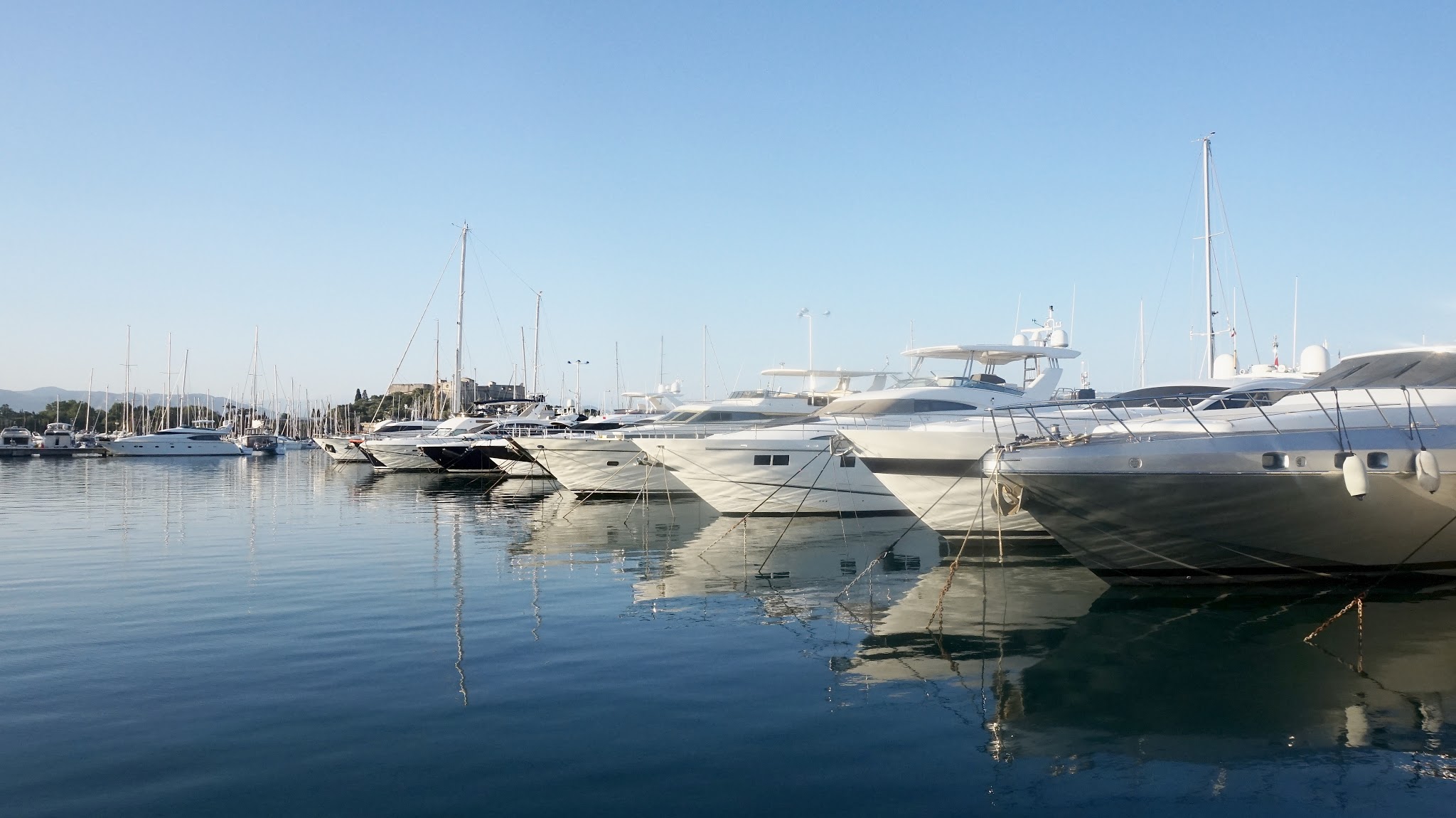expensive looking yachts in a harbour, blue sea and sky