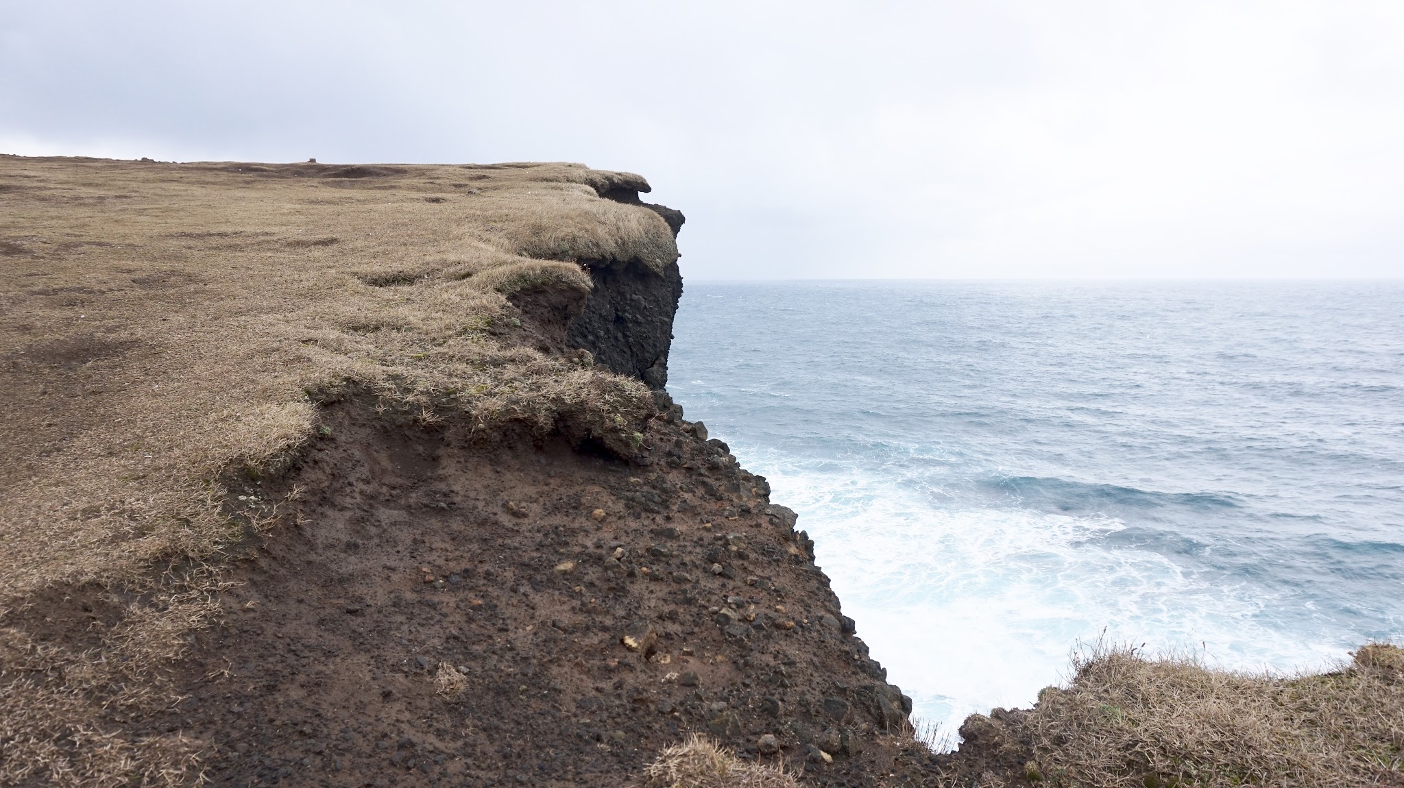 cliffs looking down onto icy blue waves, choppy