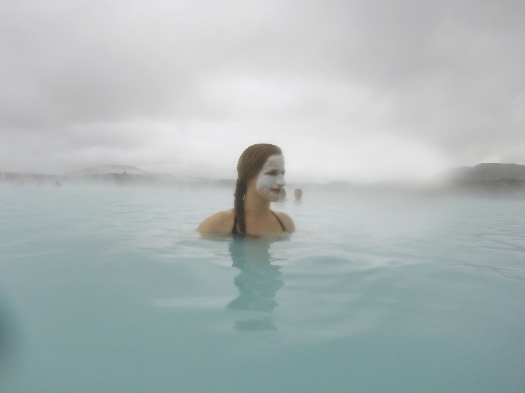 woman in face mask looking out on the water at the Blue Lagoon