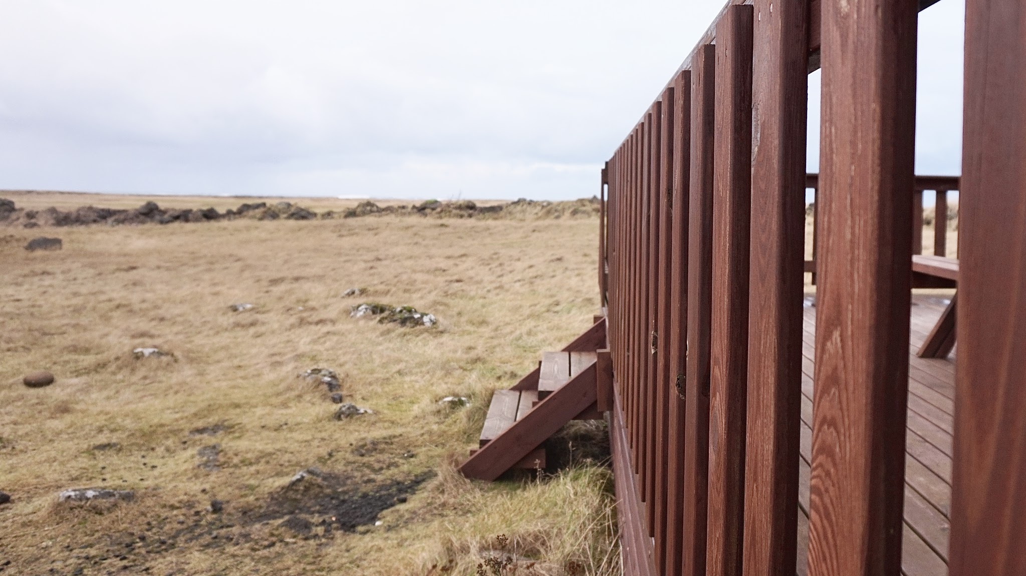 Iceland log cabin wooden steps leading up to a log cabin, against the backdrop of a rural grassy expanse